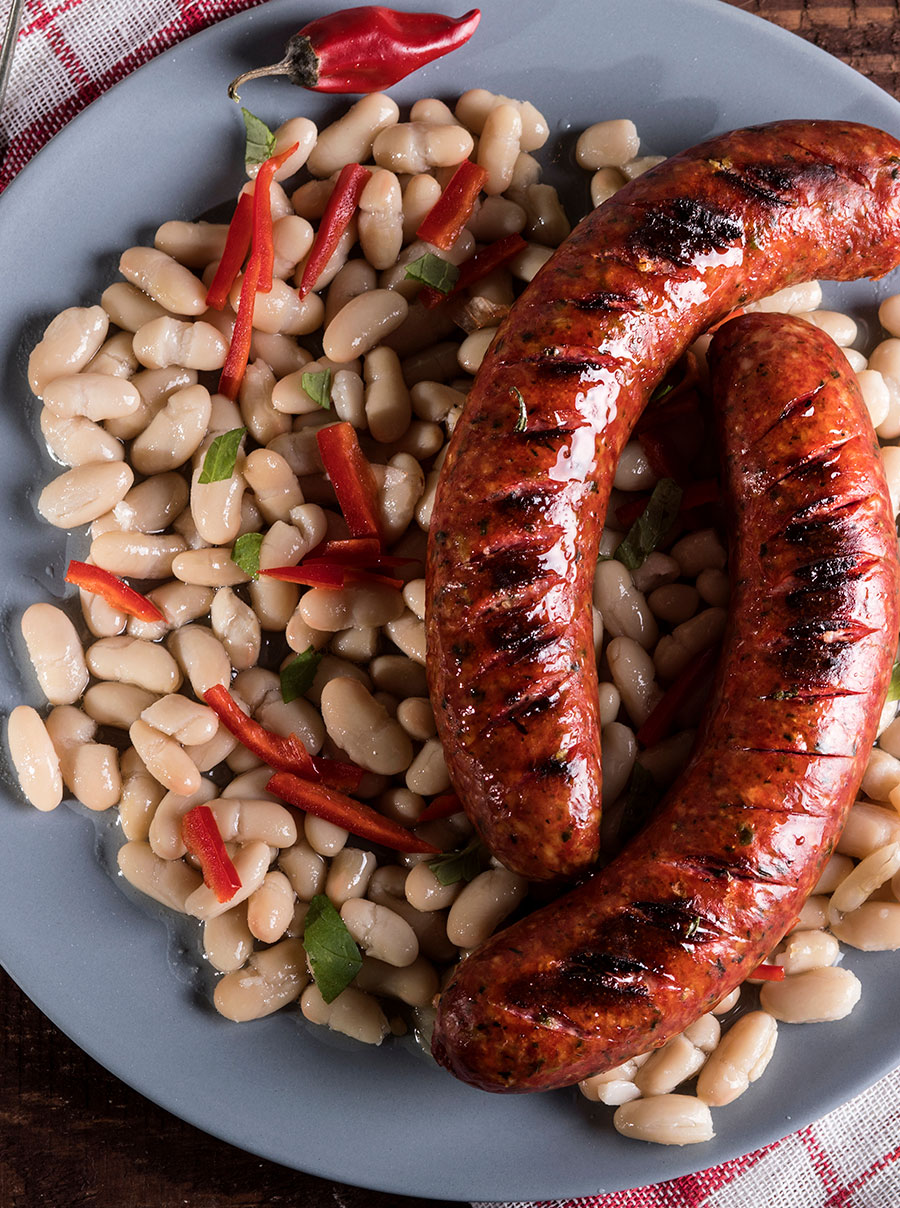 Plato de judías blancas estofadas (o fesols amb botifarra) con trozos de chorizo o salchicha a la parrilla, ilustrando la opción del menú del día.